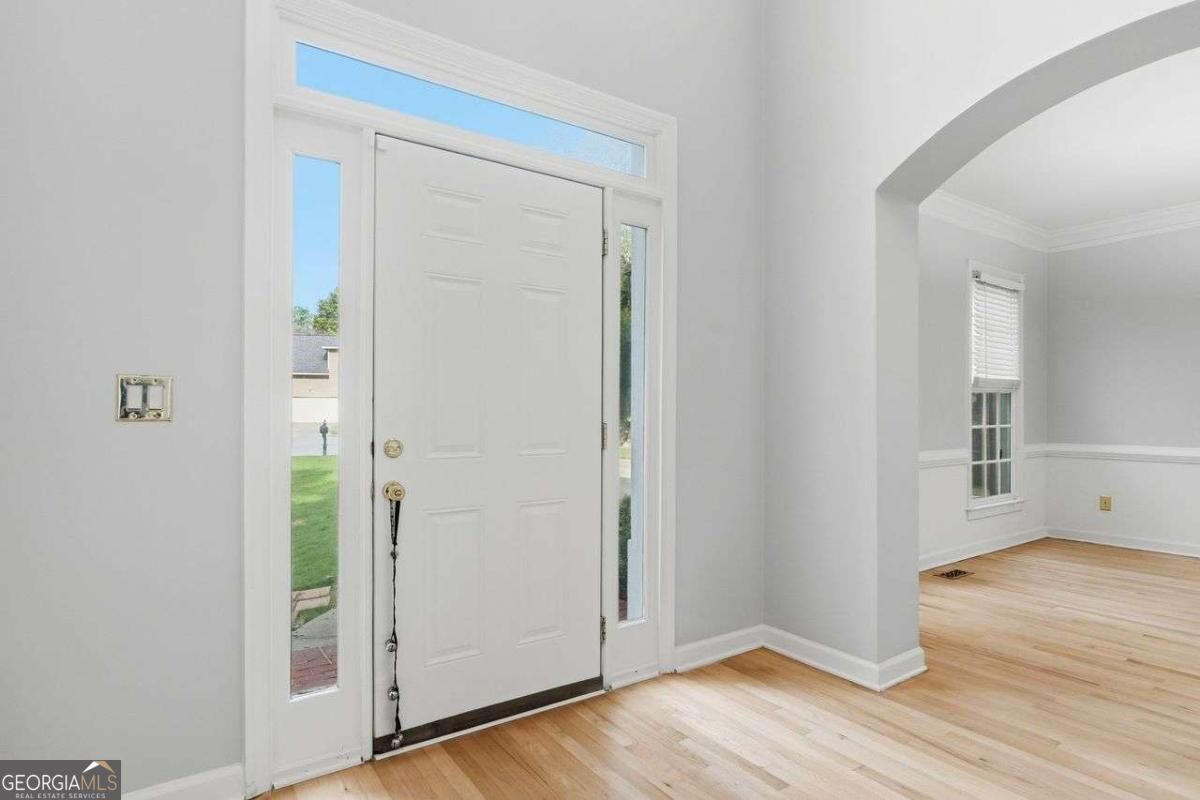 Entry foyer with a white front door, sidelights, transom window, and light hardwood floors.