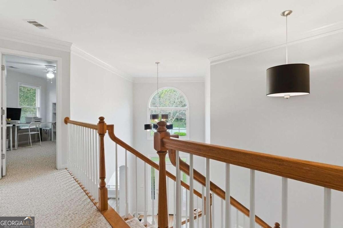 Upstairs landing with a carpeted hallway, wood-and-white stair railing, and arched window.