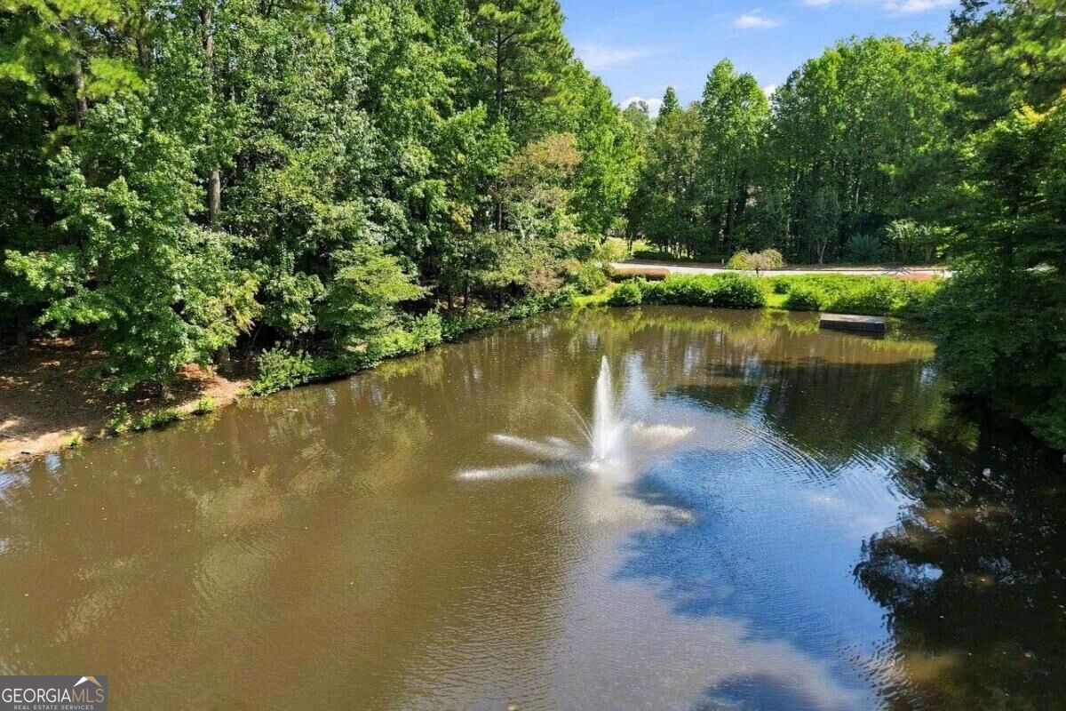 Tree-lined pond with a central fountain and a small platform over the water.