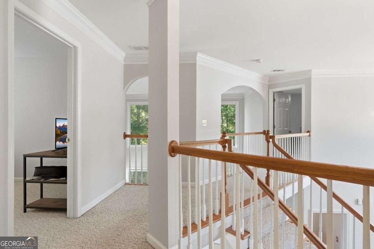 Upstairs hallway landing with arched openings and a wooden stair railing.