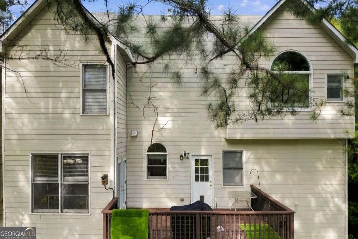 Rear of the home with a raised wooden deck and pine branches crossing the view.