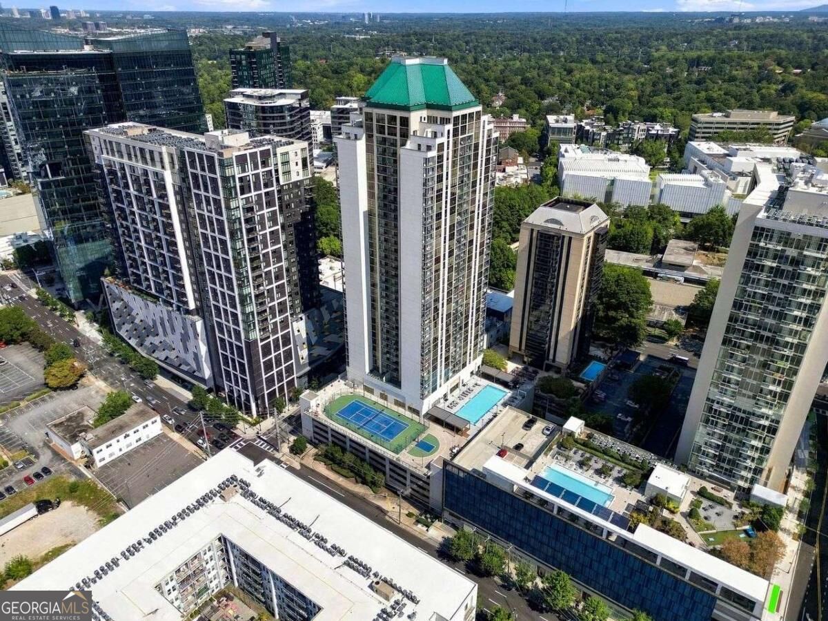 Aerial view of high-rise buildings with rooftop pools and a tennis court.