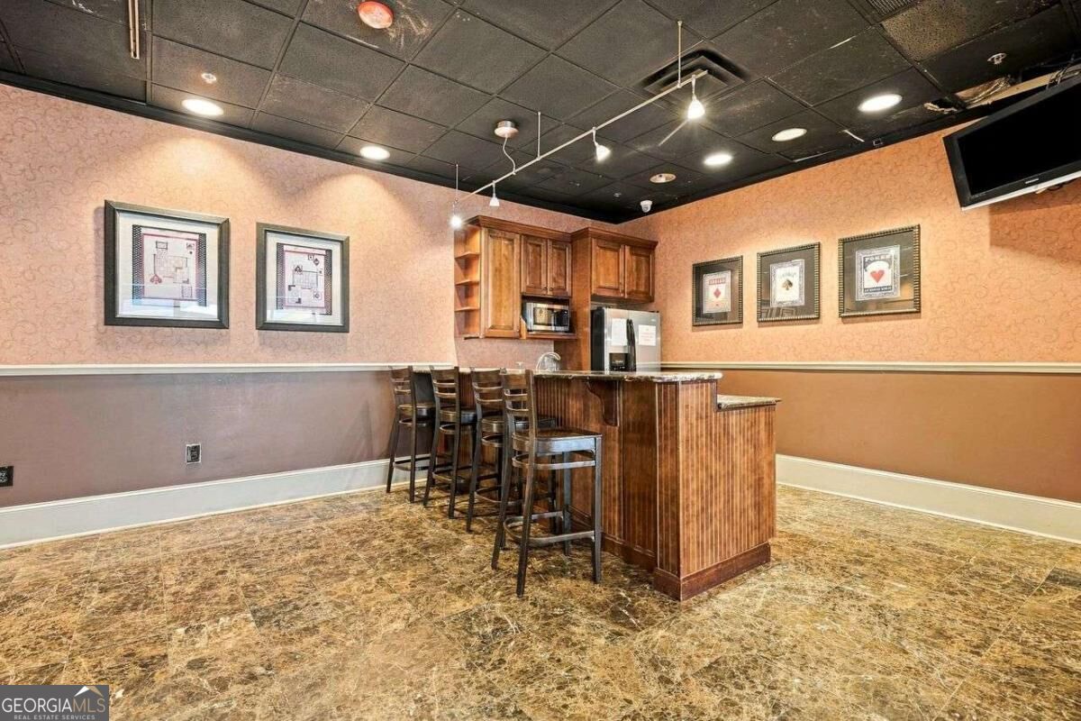 Kitchenette with wood cabinetry, a bar island, and stools.