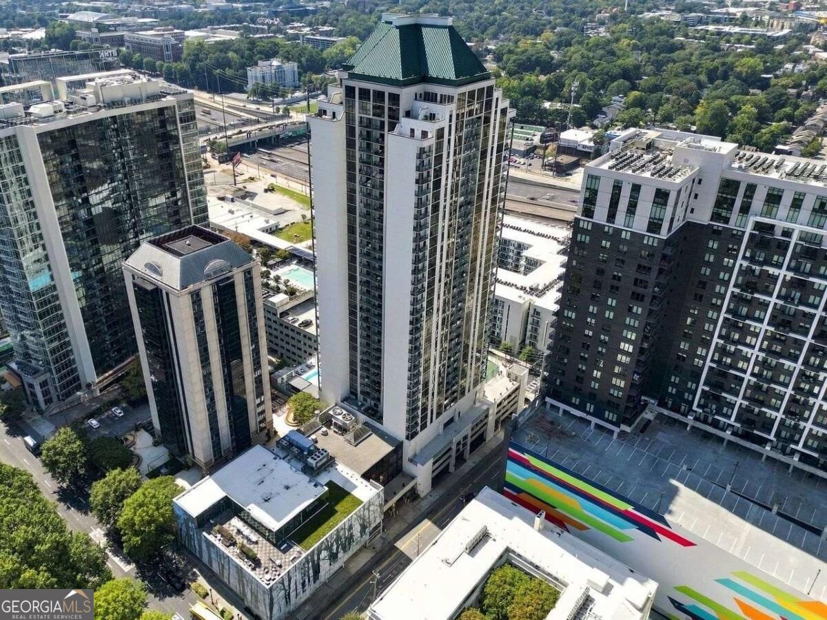 Aerial view of Atlanta high-rises, with a white tower topped by a dark green peaked roof and a rainbow-striped parking deck.