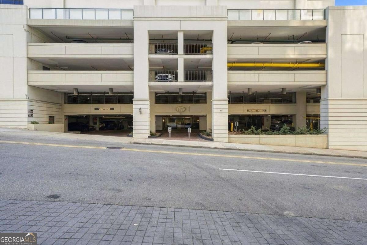 Multi-story parking garage with a central entrance and planted beds along the street-facing facade.