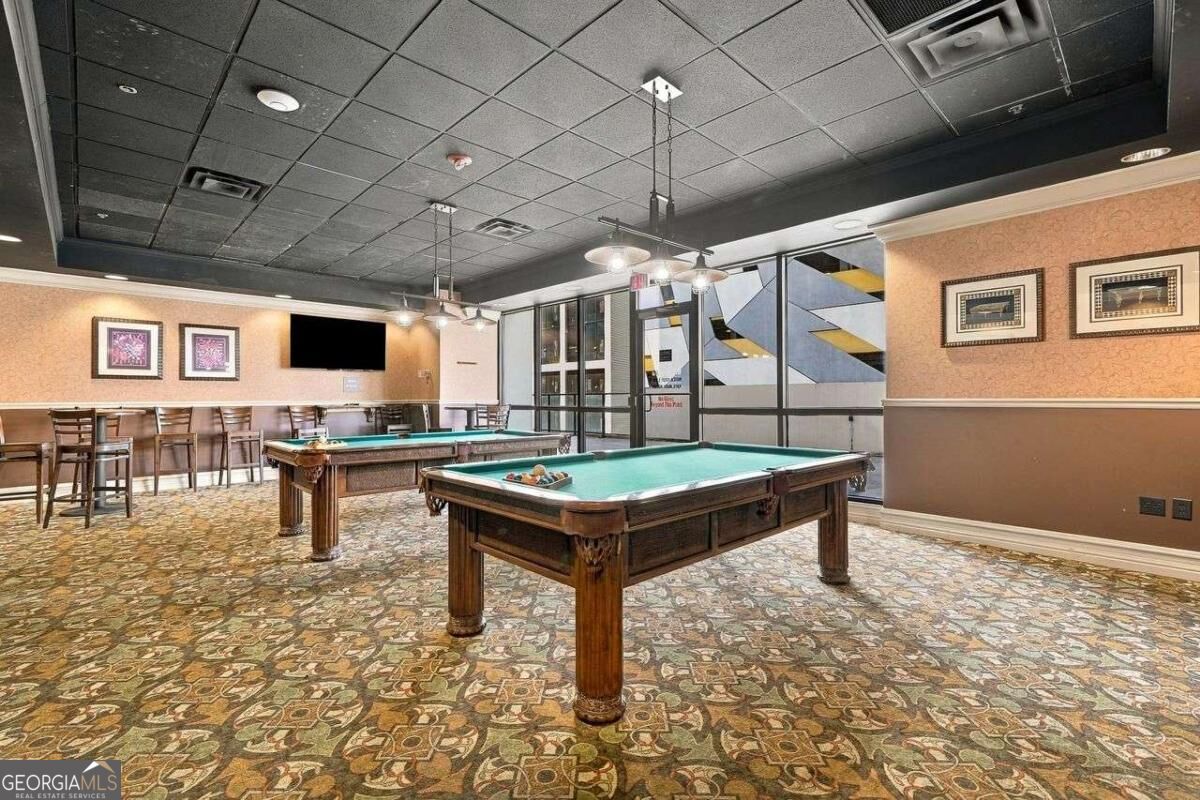 Billiards room with two pool tables, counter seating, and patterned carpet.