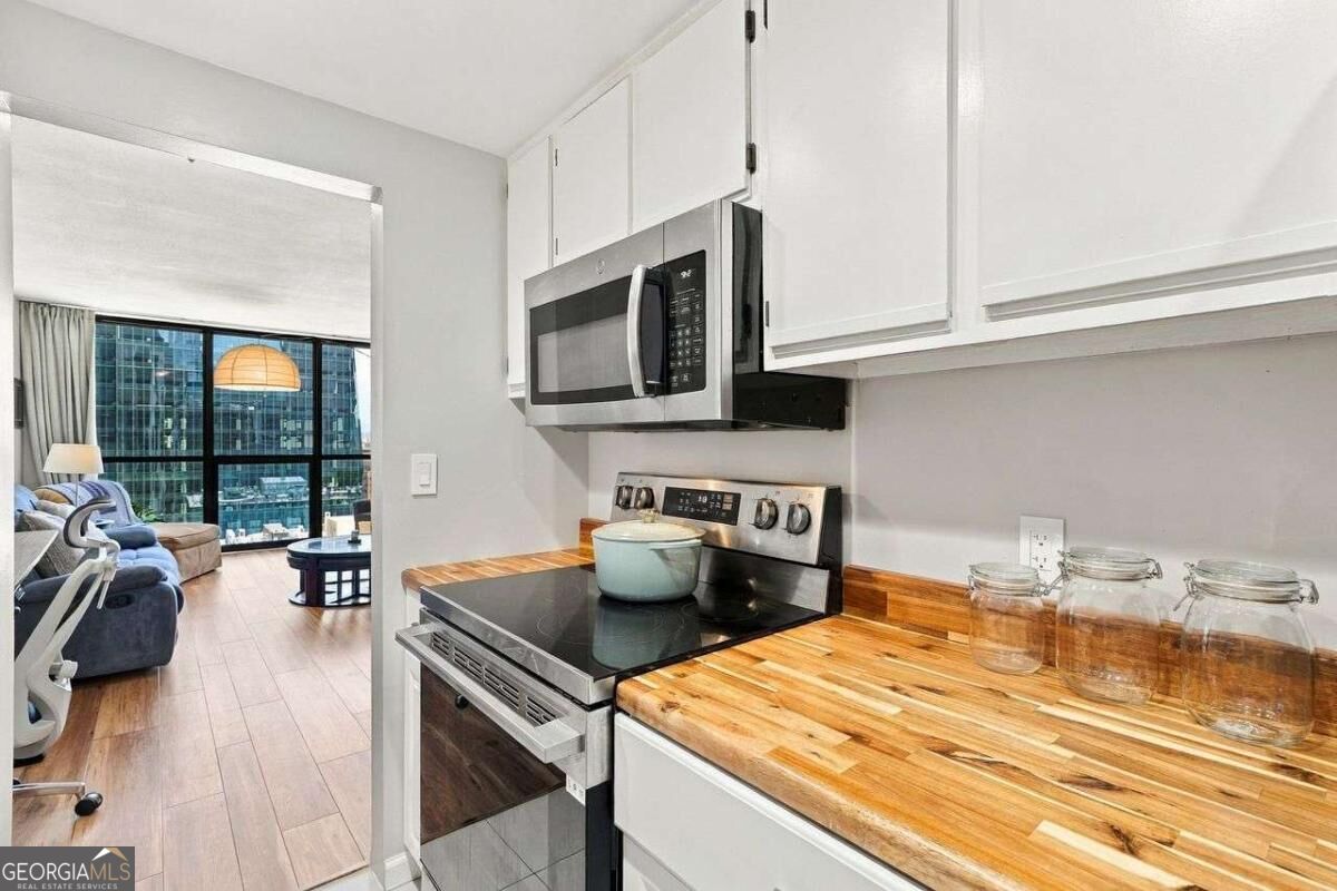 Condo kitchen with butcher-block counters and stainless appliances opening to a living area with city views.