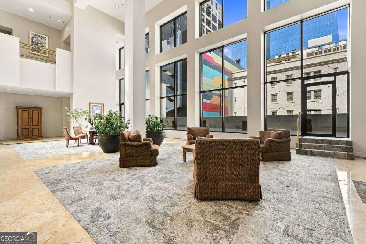 Condominium lobby with tall windows, lounge seating, and views of nearby buildings.