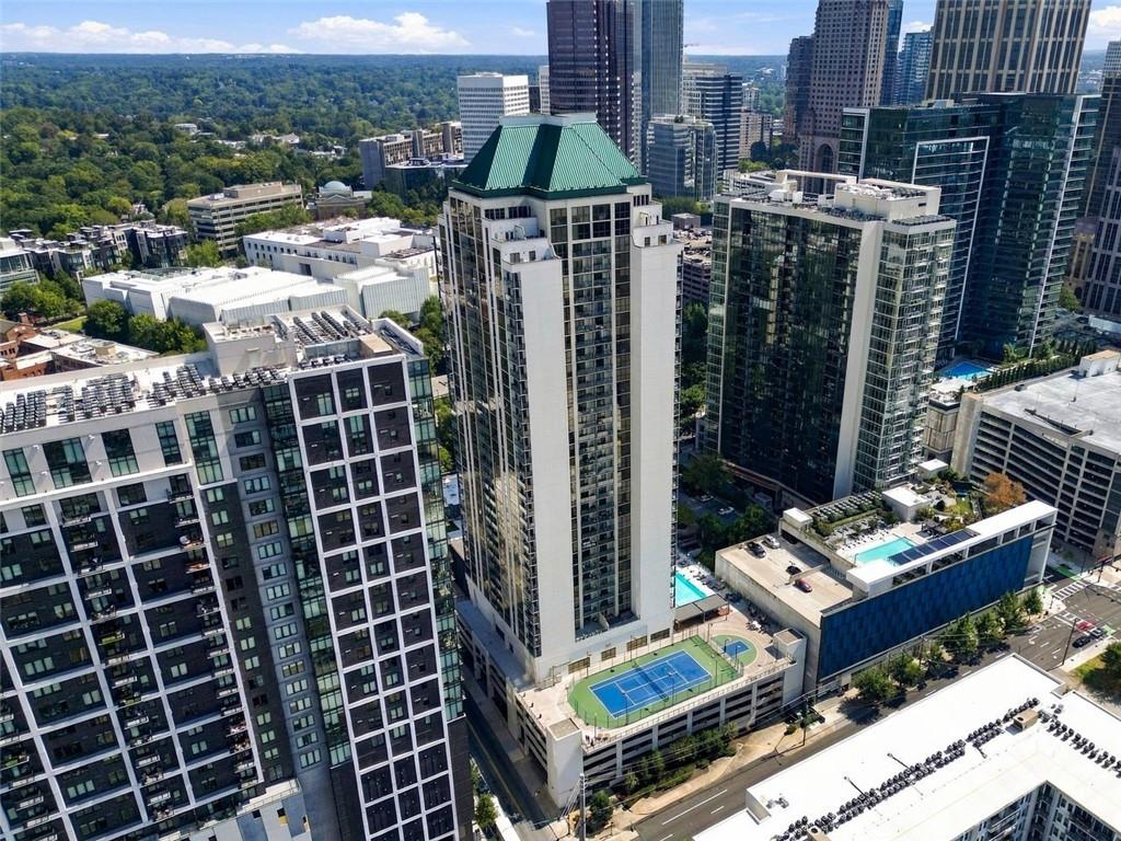 Aerial view of Atlanta high-rises with a green-roofed tower and rooftop tennis courts.