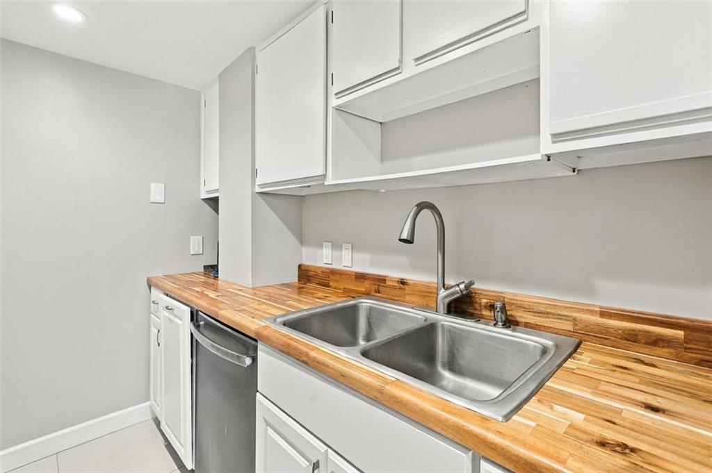 Kitchen with a butcher-block counter, double-basin sink, and stainless steel dishwasher.