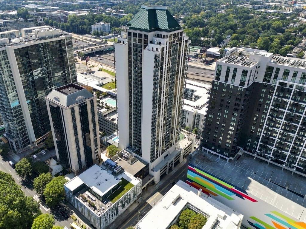 Aerial view of a high-rise residential tower with a green roof among surrounding buildings.