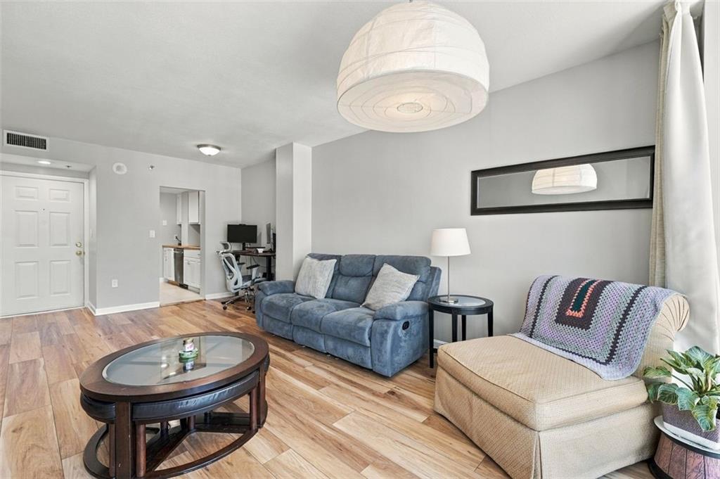 Condominium living room with a blue sofa, beige armchair, and wood-look flooring.