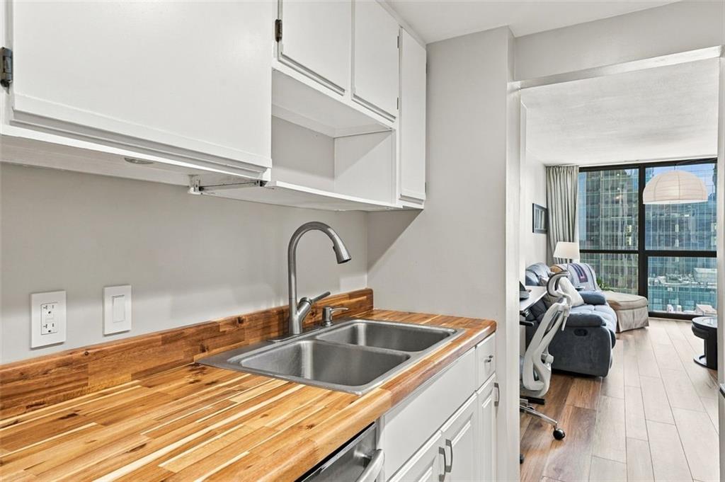 Condo kitchen with butcher-block counters and a double sink opening to a windowed living area.
