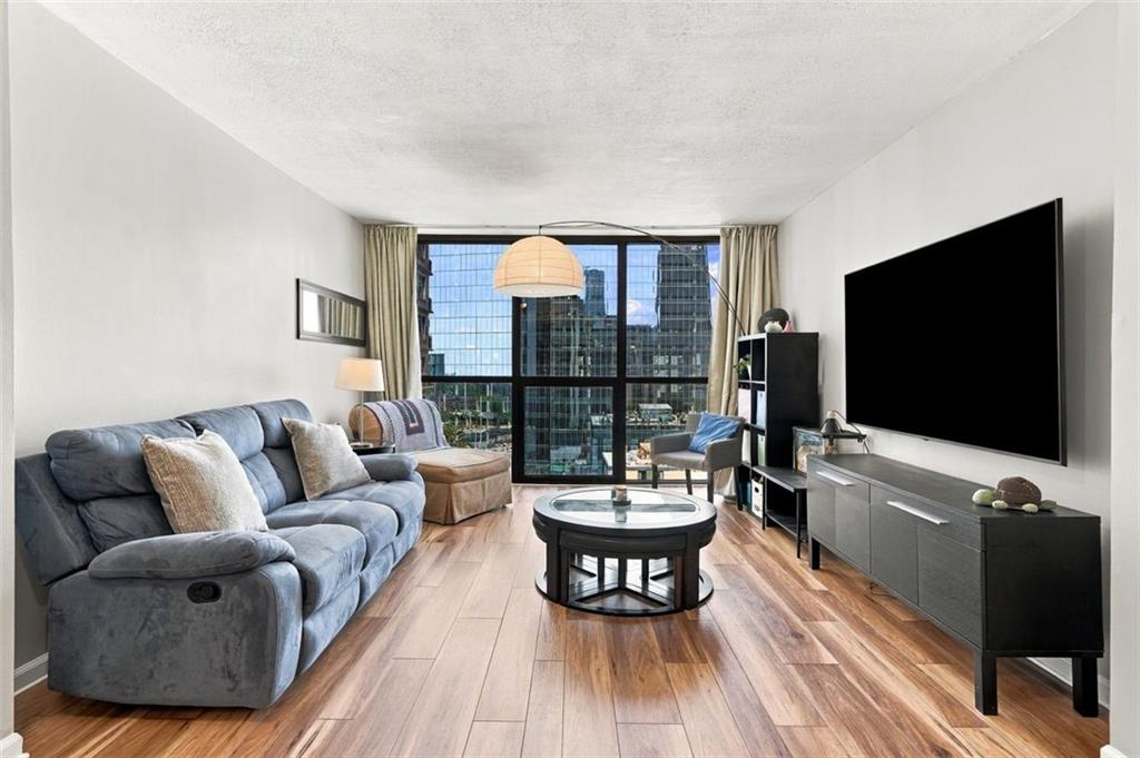 Living room with a blue sectional sofa, round coffee table, and city skyline views through large windows.