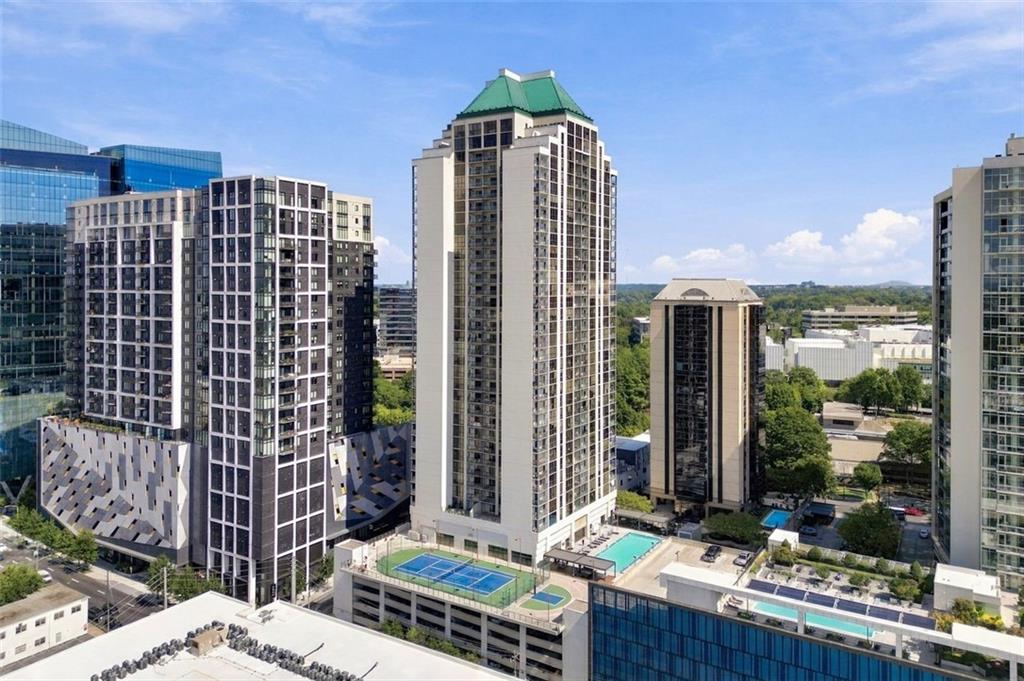 High-rise residential towers with rooftop pools and a tennis court below.