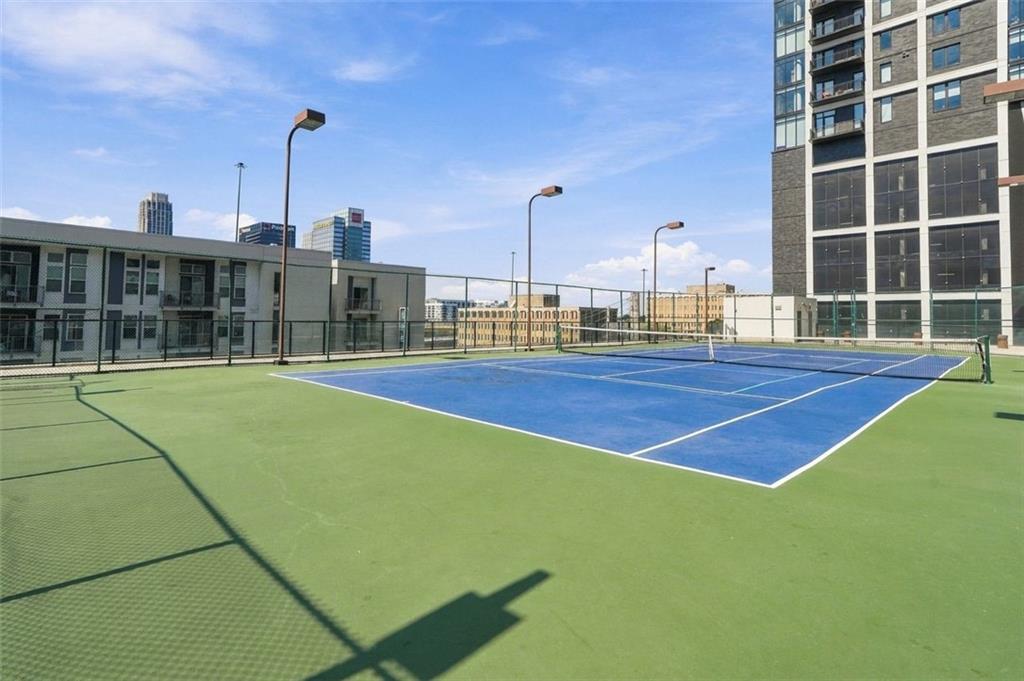 Elevated tennis court beside apartment buildings, with the Atlanta skyline in the distance.