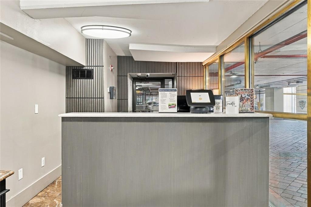 Lobby reception desk with a computer terminal and glass doors to a paved walkway.