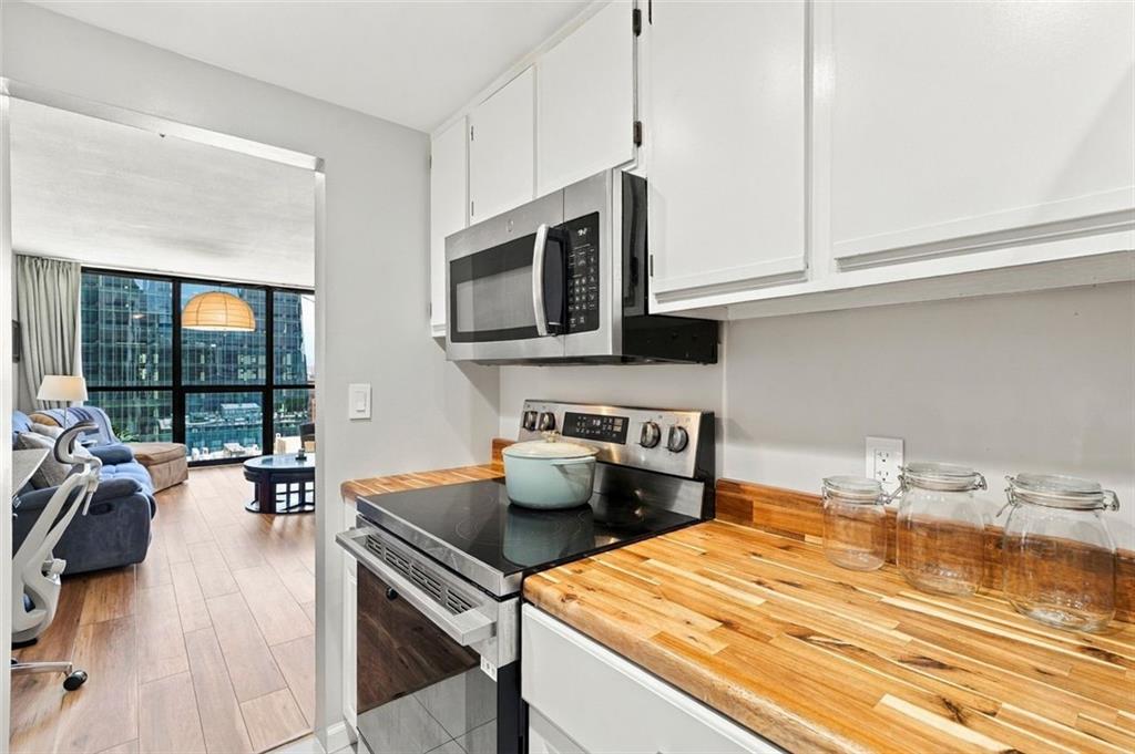 Condo kitchen with butcher-block counters and stainless appliances, opening to a city-view living area.