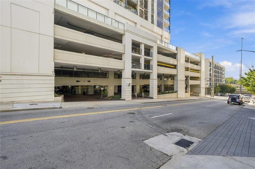 Multi-story parking garage beneath a high-rise, viewed from across the street.