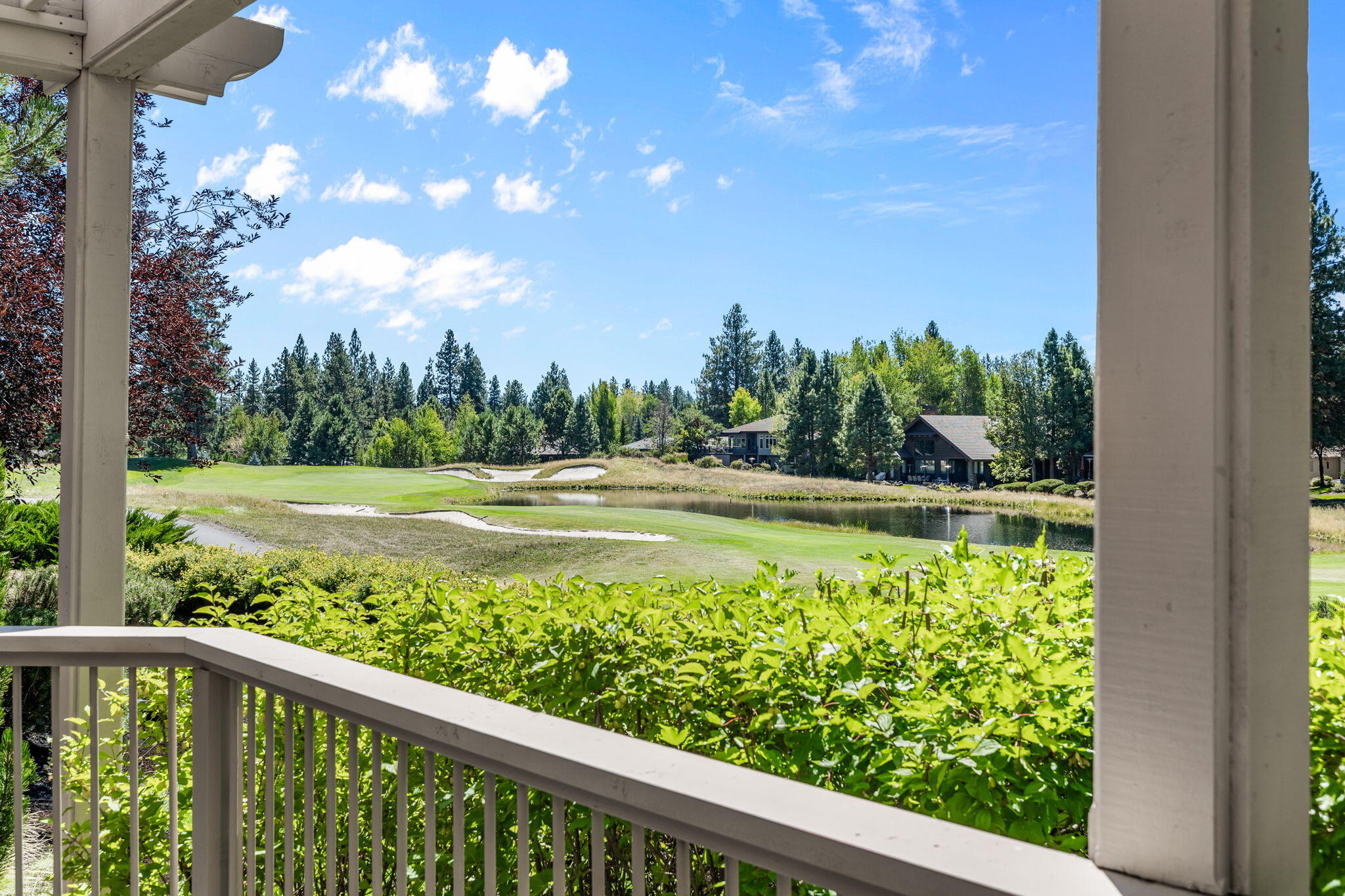 Porch overlooking a golf course and pond, with sand bunkers and homes among the trees.