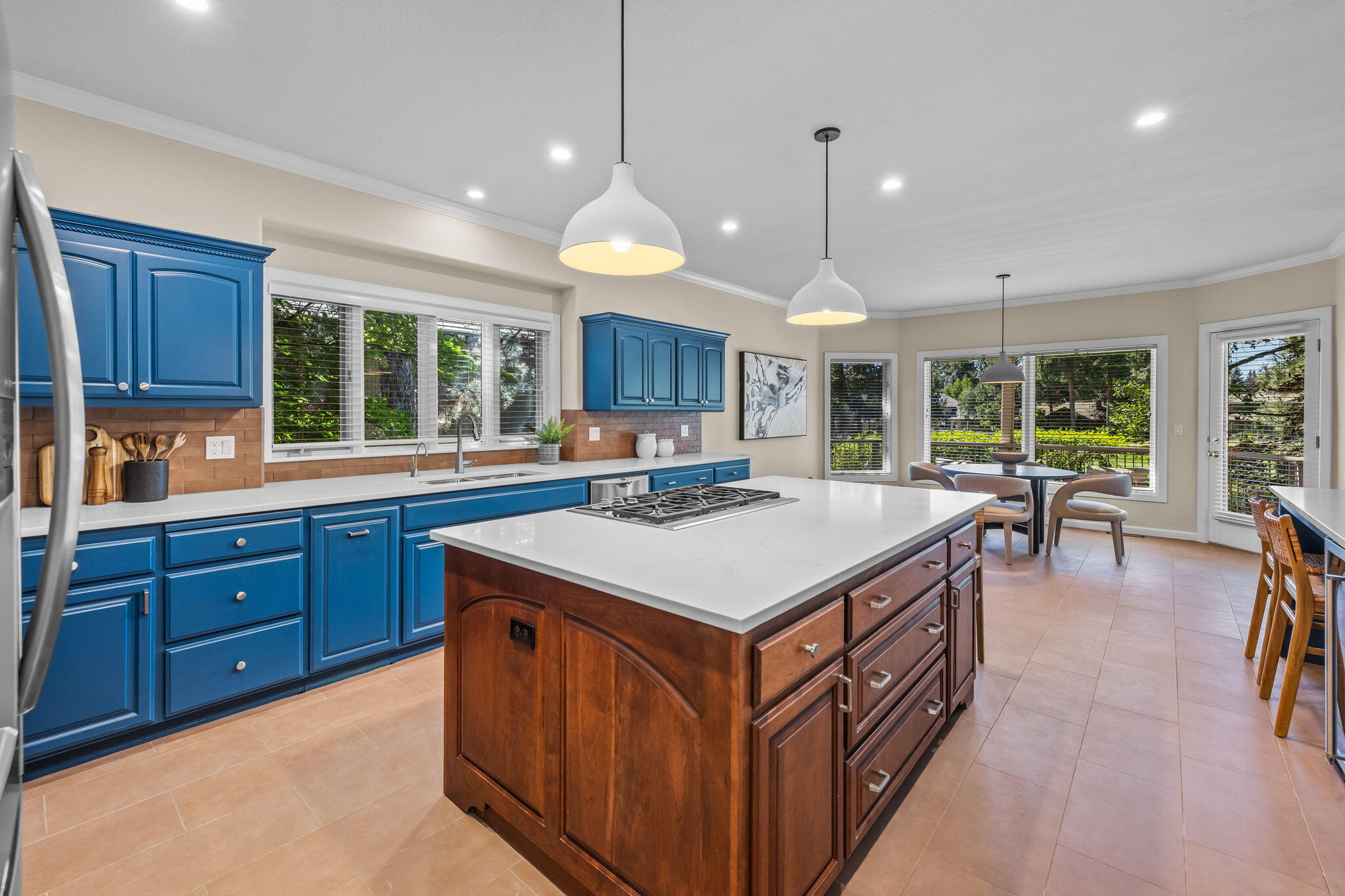Kitchen with blue cabinets, a large wood island, and a window-side dining nook.