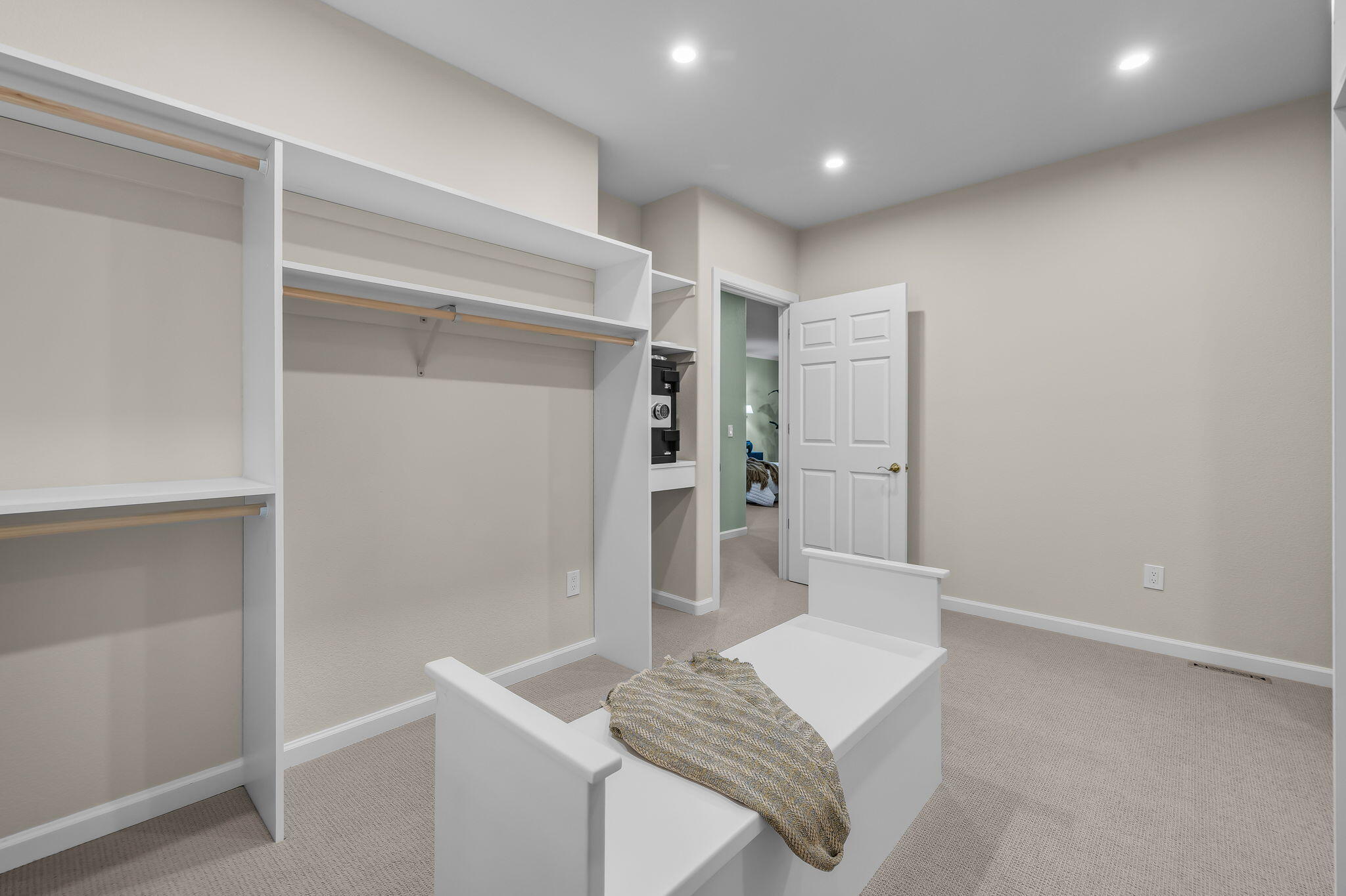 Bedroom with open built-in closets and a white bed with a patterned throw.
