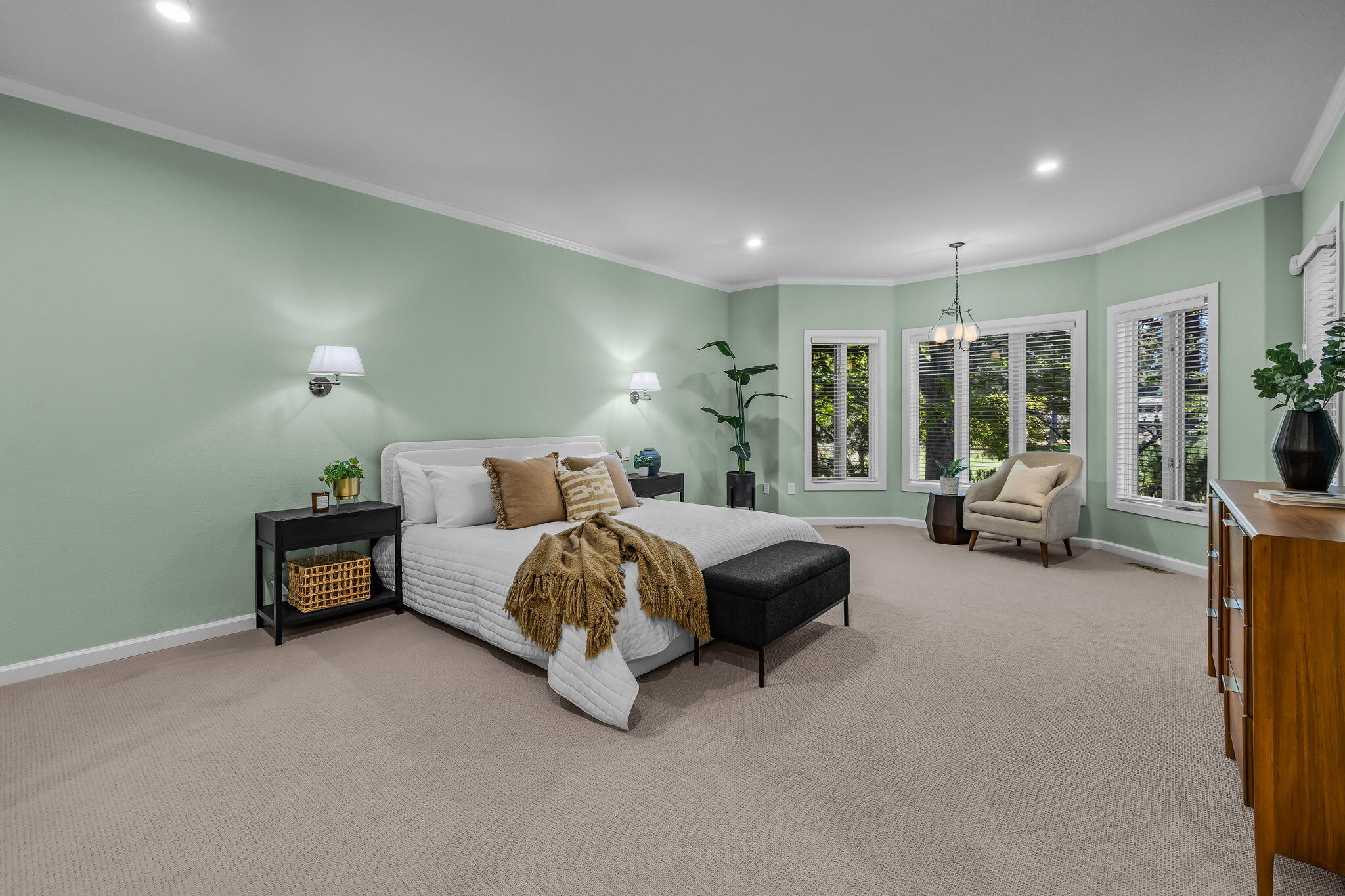 Furnished bedroom with sage green walls, a white bed, and shuttered windows.
