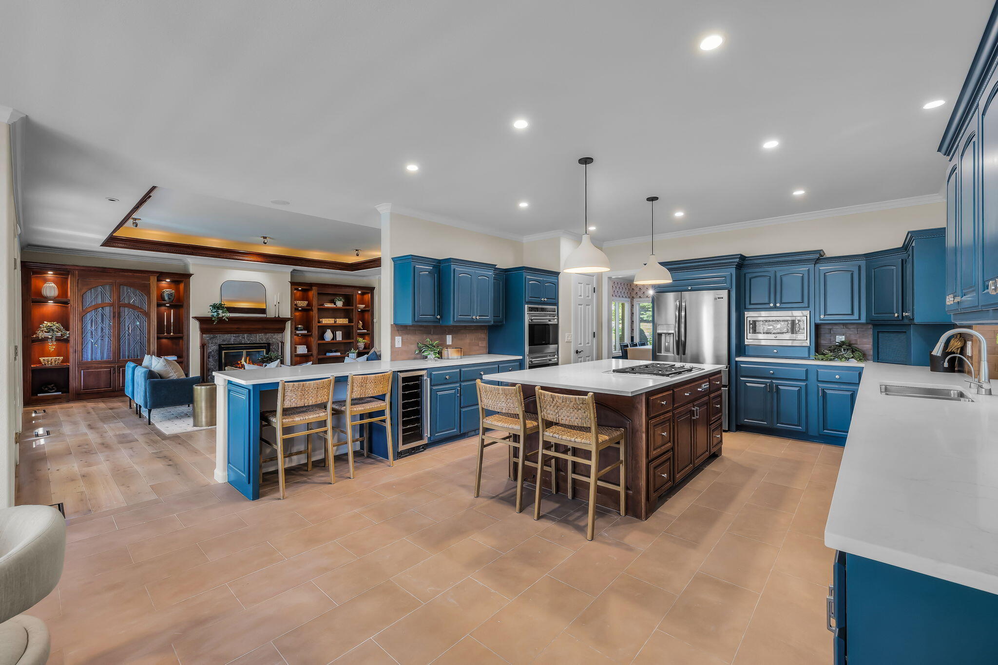 Spacious kitchen with blue cabinetry, a large island, and an adjoining living area with a fireplace.