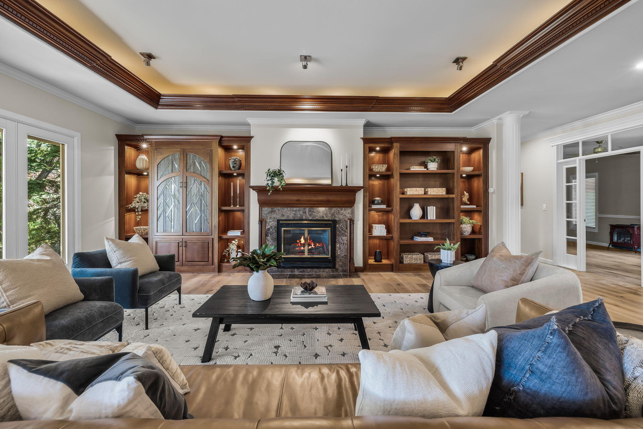 Living room with a lit fireplace, built-in wood shelves, and ornate ceiling trim.