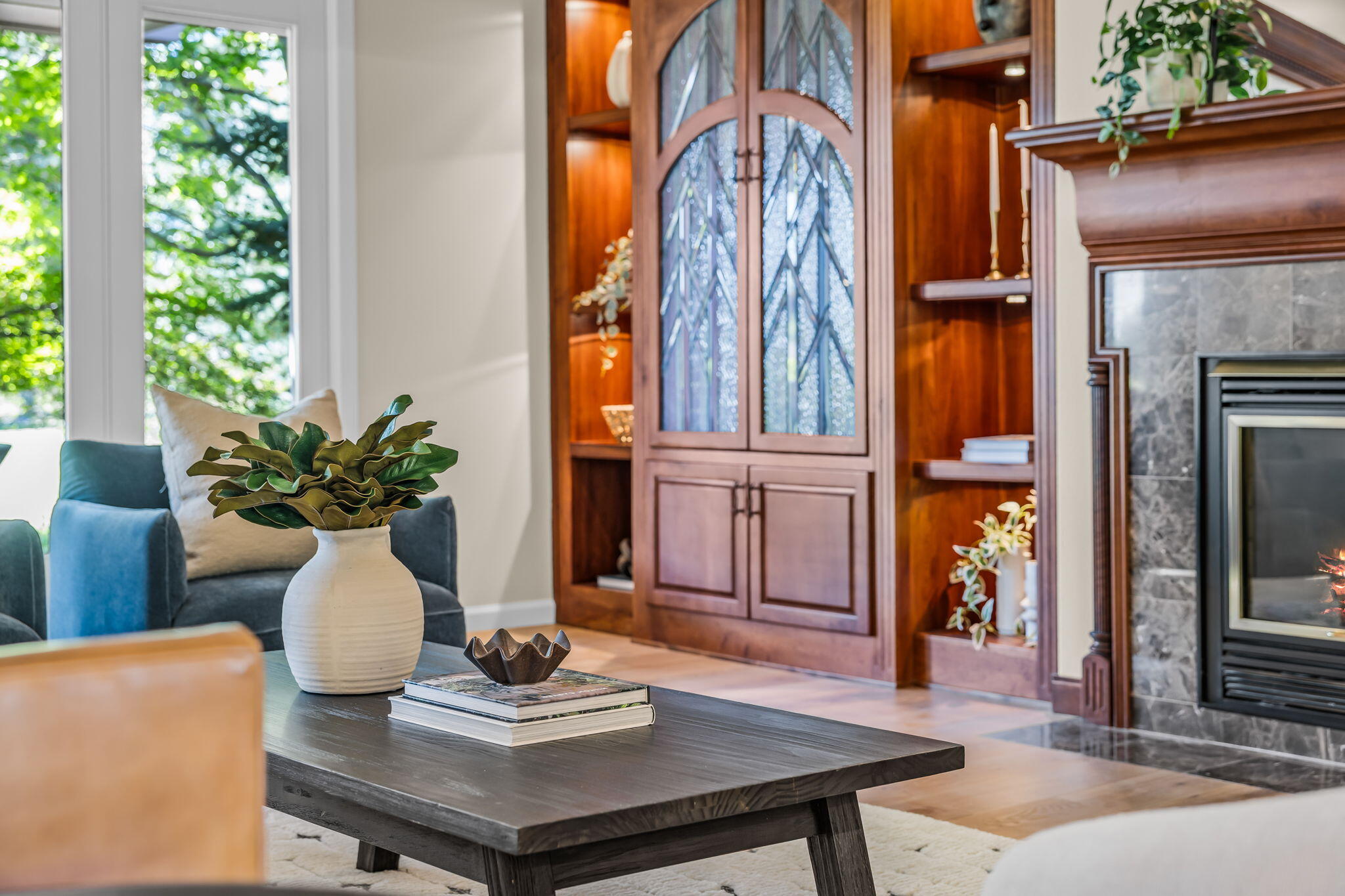 Living room with a leaded-glass wood cabinet, stone fireplace, and blue armchair.