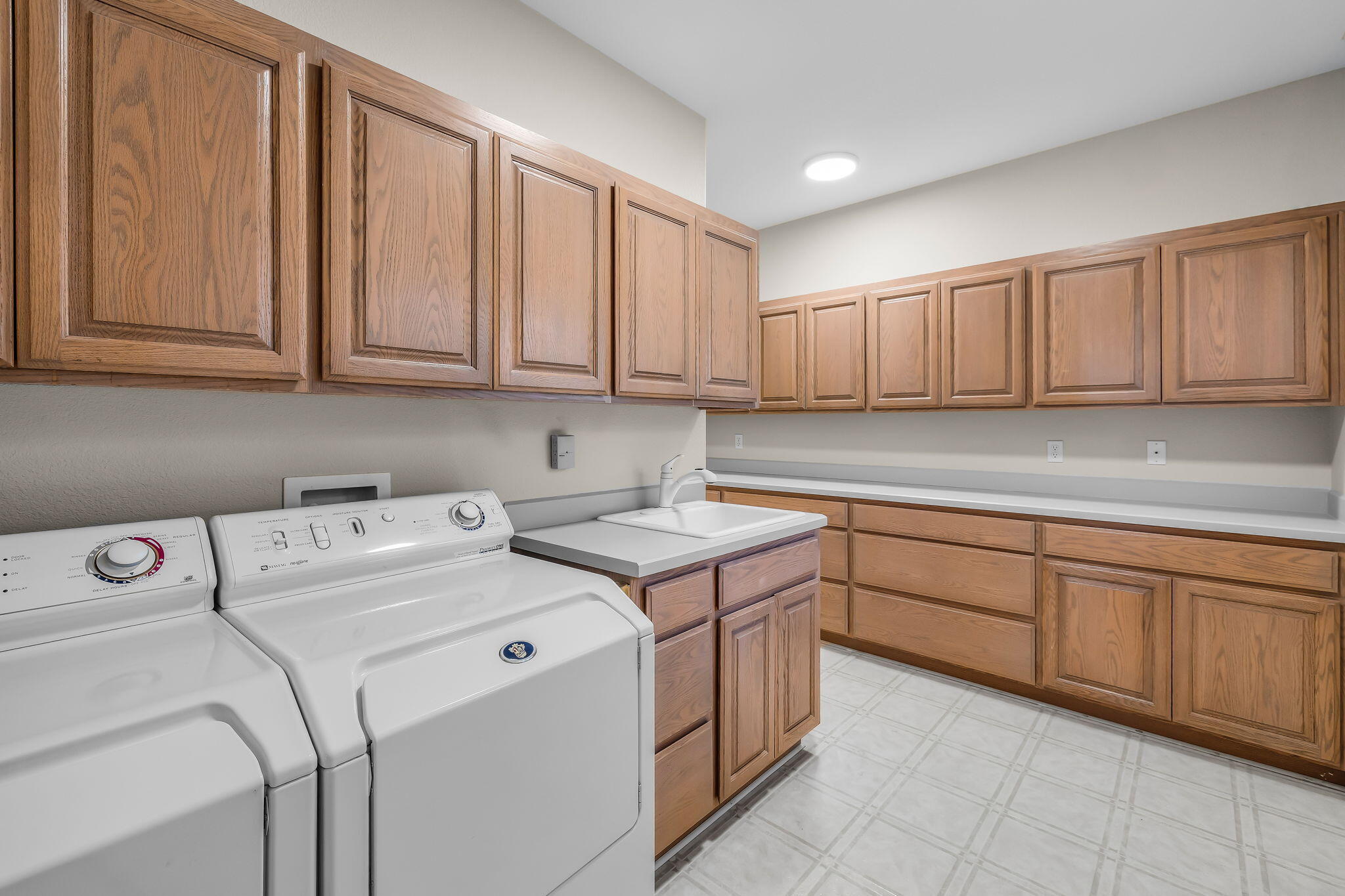 Laundry room with extensive wood cabinetry, washer and dryer, and utility sink.
