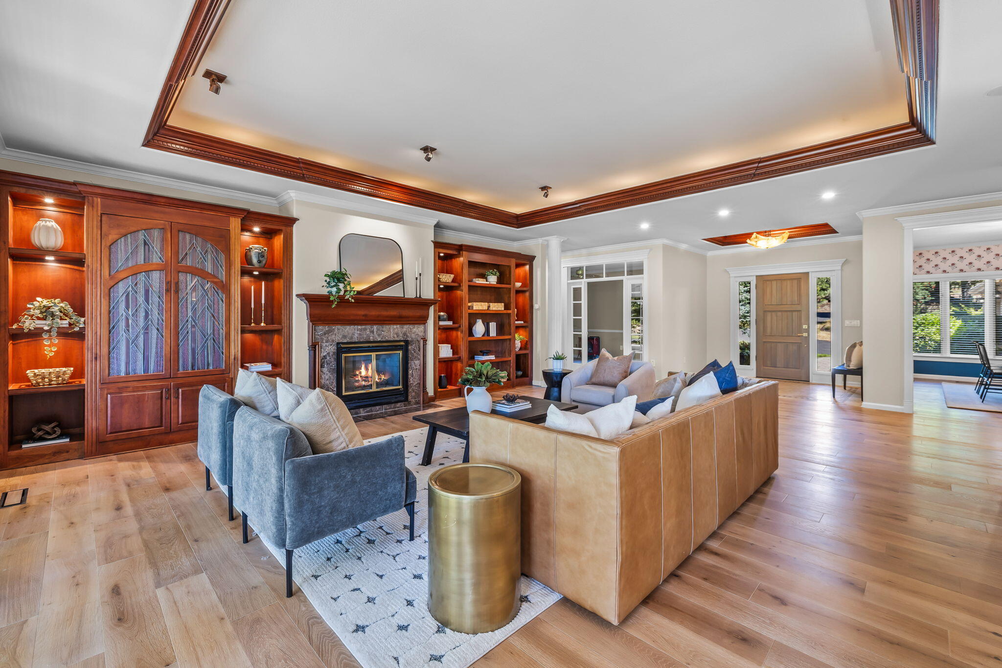 Furnished living room with built-in wood shelves, a stone fireplace, and a coffered ceiling.