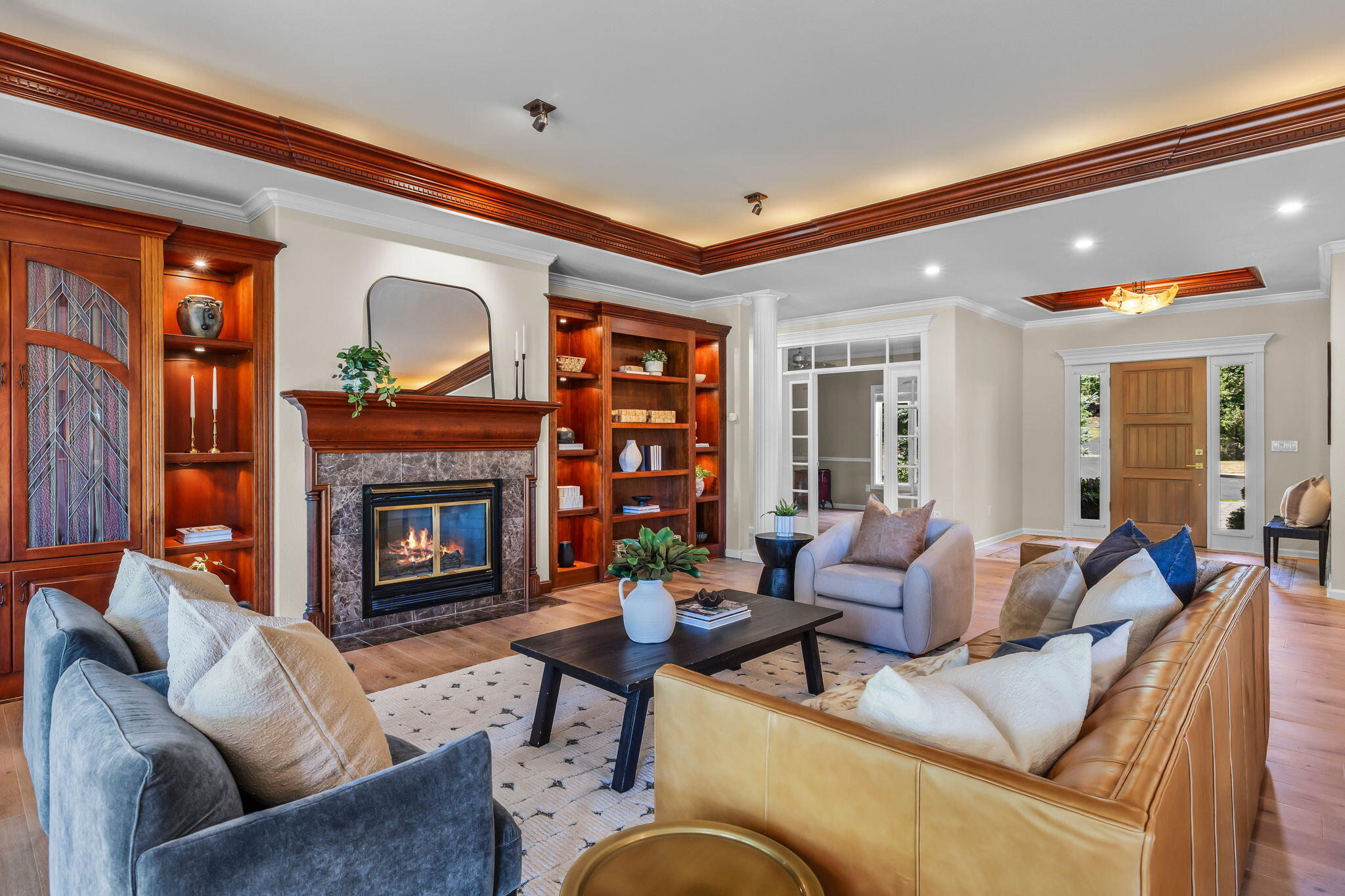 Living room with a marble fireplace, built-in wood shelves, and blue and tan sofas.