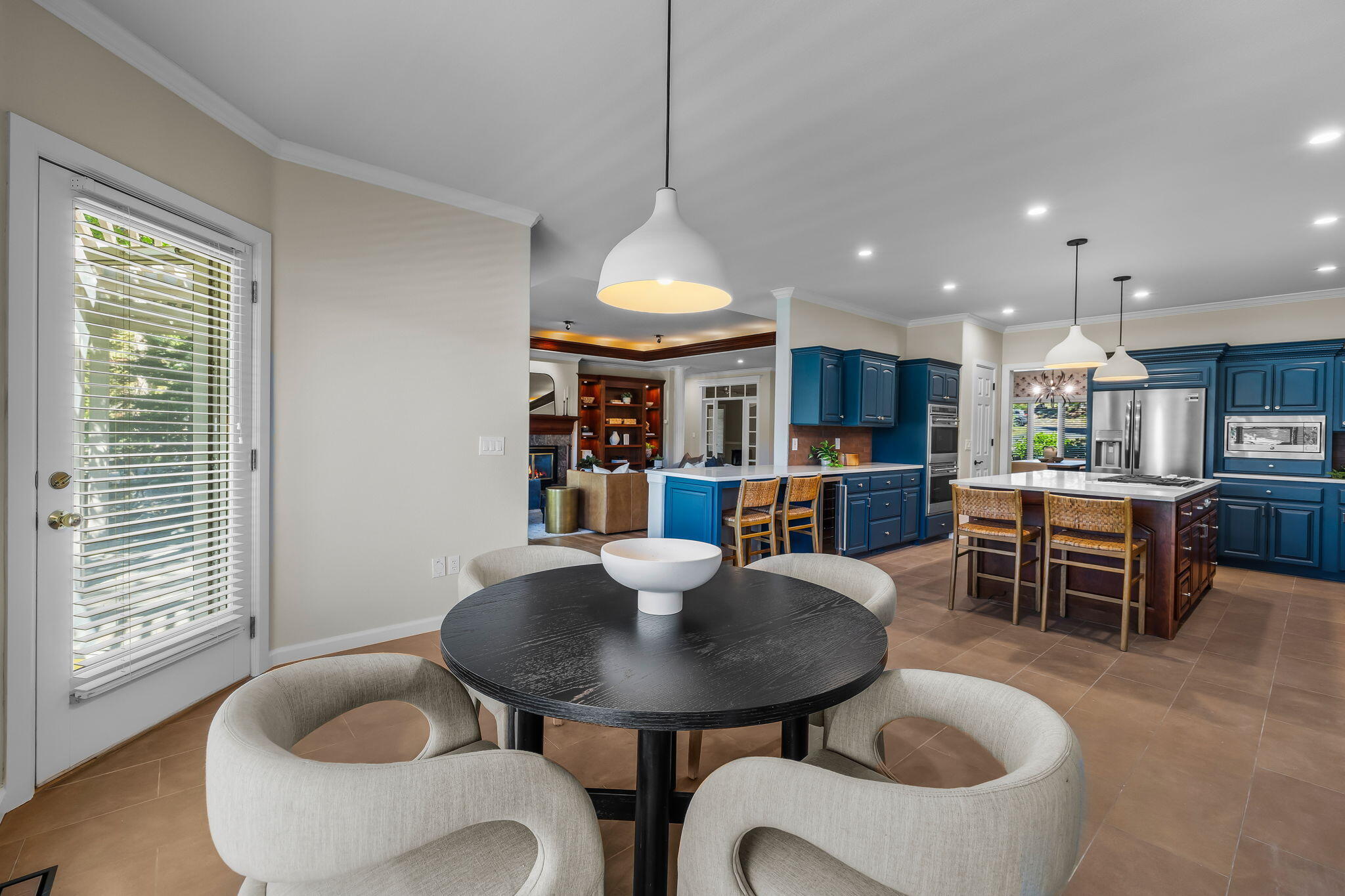 Open kitchen with deep blue cabinets and island, viewed past a round dining table.