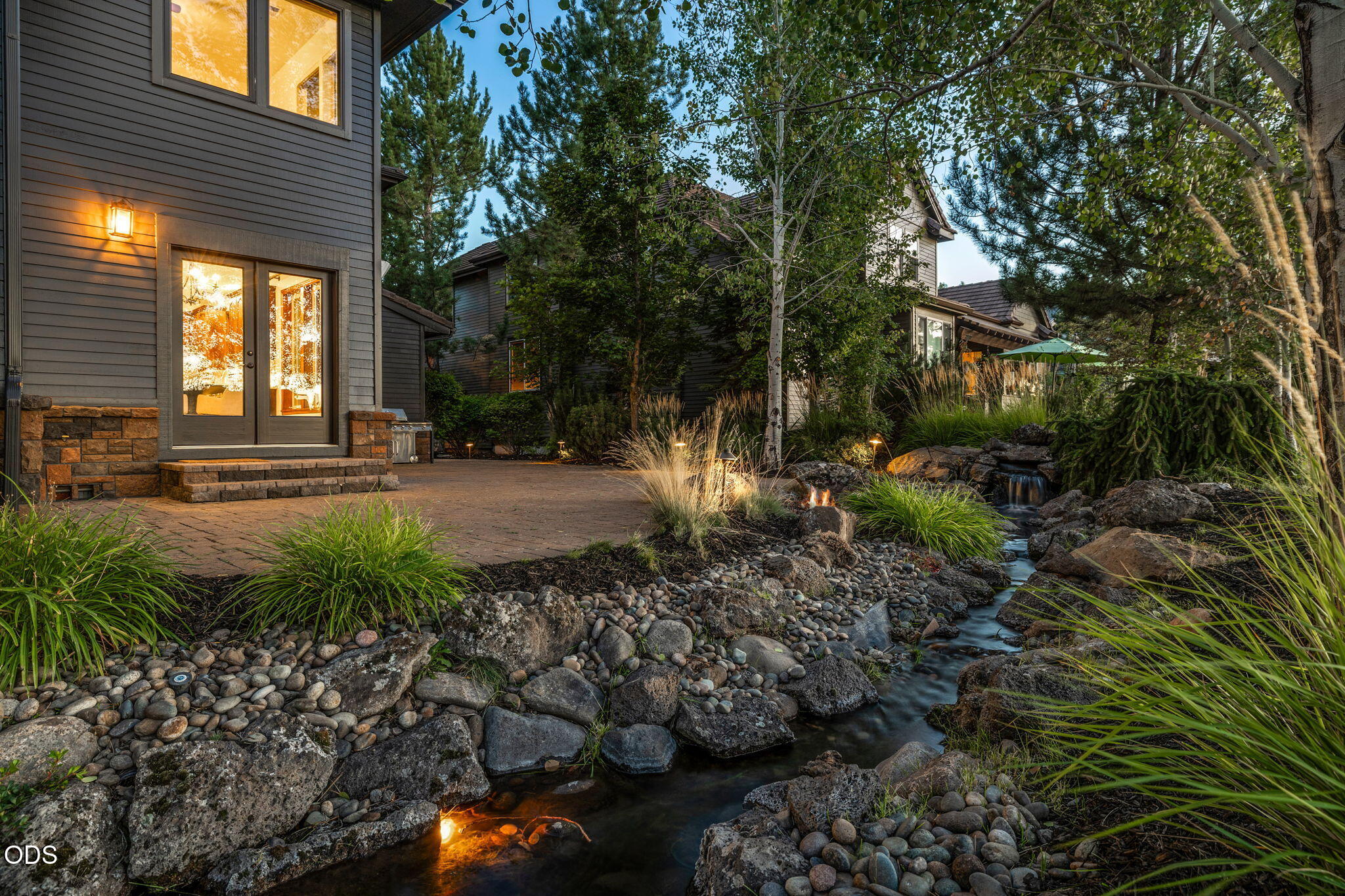 Home exterior beside a landscaped patio with a rock-lined stream and small waterfall.