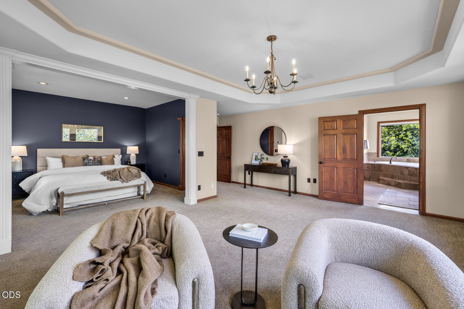 Primary bedroom with a navy accent wall, tray ceiling, and doorway to the ensuite bathroom.