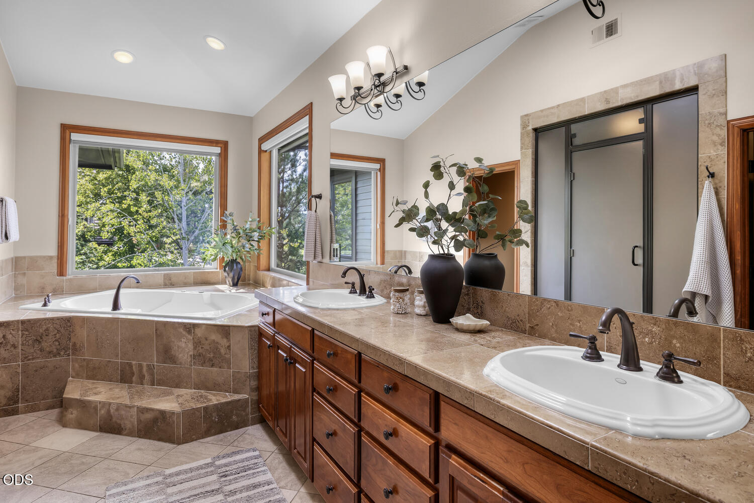 Primary bathroom with a corner soaking tub, double-sink vanity, and glass-enclosed shower.