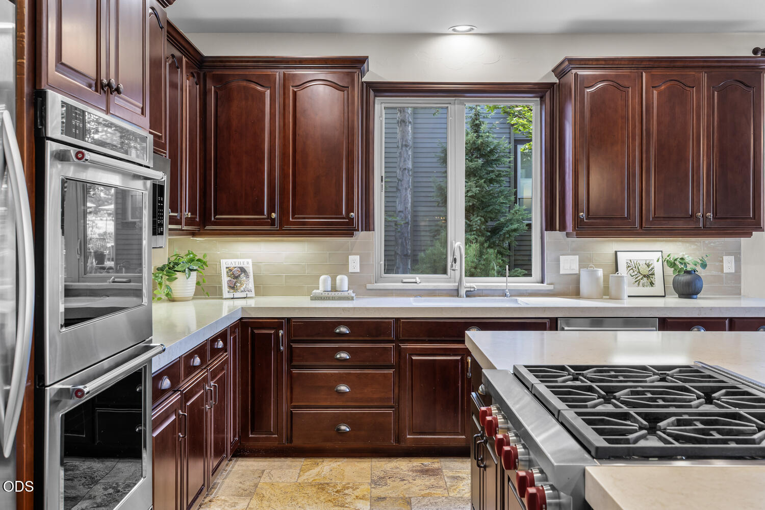 Kitchen with dark wood cabinets, stainless steel double ovens, and a large gas cooktop.