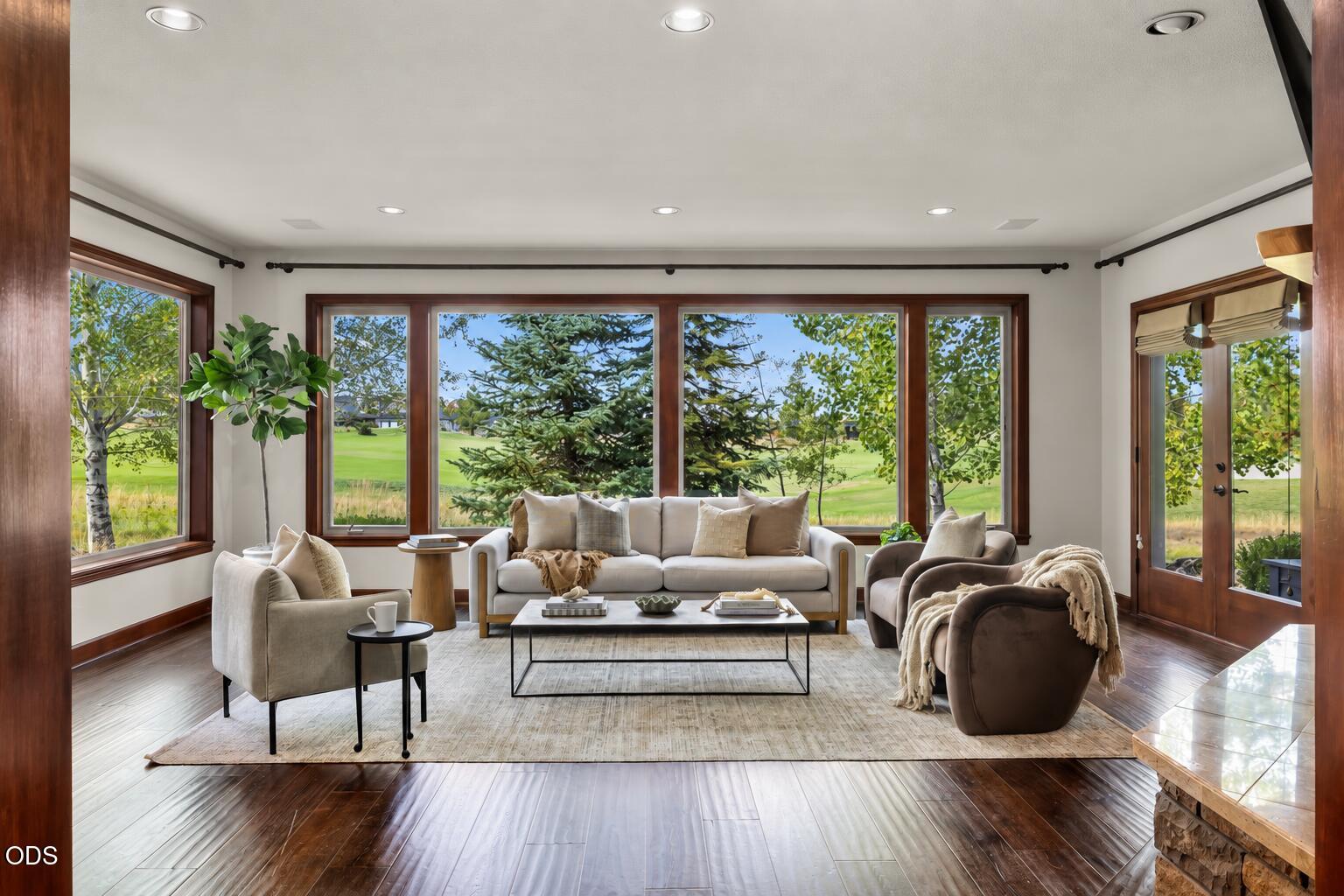 Living room with expansive golf course views through large windows and a glass door.