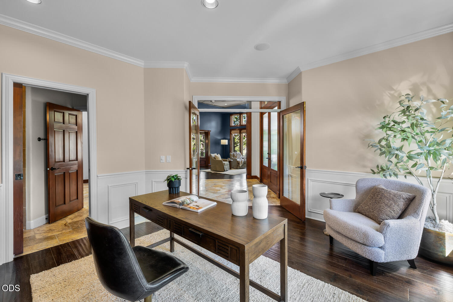 Staged home office with a wood desk and open doors to a blue-walled sitting room.