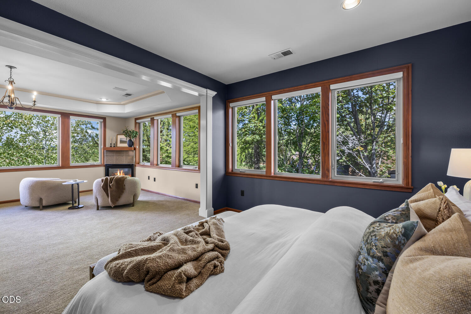 Bedroom with large windows and an adjoining sitting area with a fireplace.