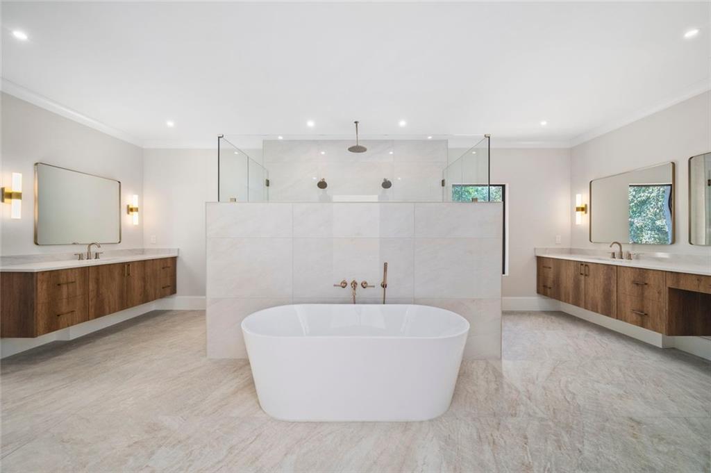 Contemporary bathroom with a freestanding soaking tub, tiled shower, and matching floating wood vanities.