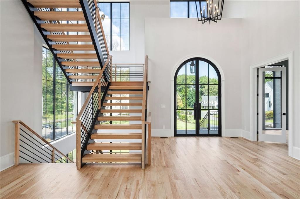 Two-story foyer with an open-riser staircase, tall windows, and an arched glass door.