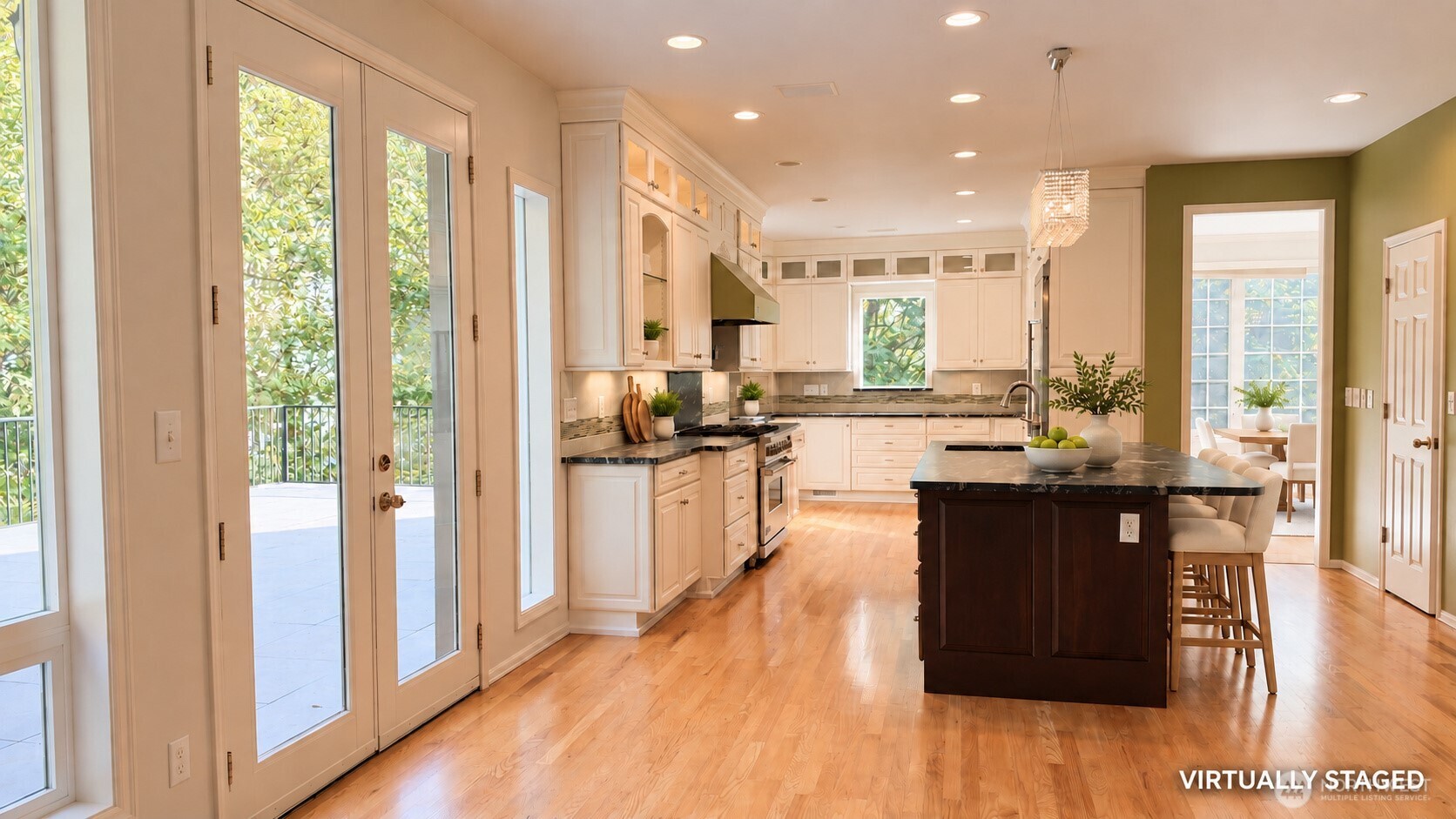 Bright kitchen with white cabinetry, a dark island and bar stools, hardwood floors, and French doors opening to greenery.