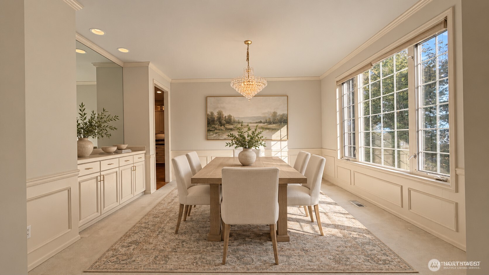 Staged dining room with a wood table, crystal chandelier, built-in cabinetry, and large windows.