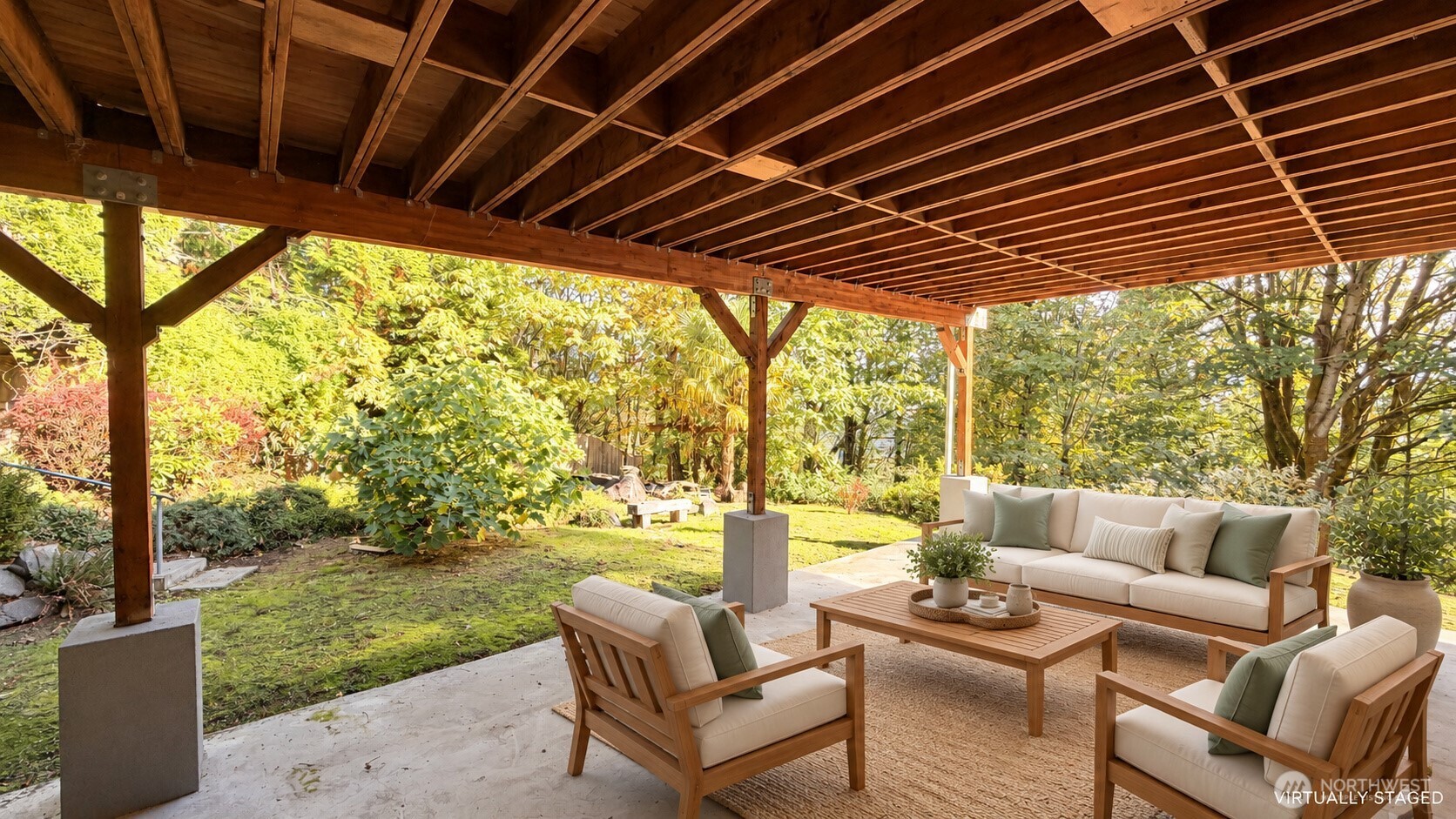 Covered patio with staged wooden lounge furniture overlooking a leafy garden.