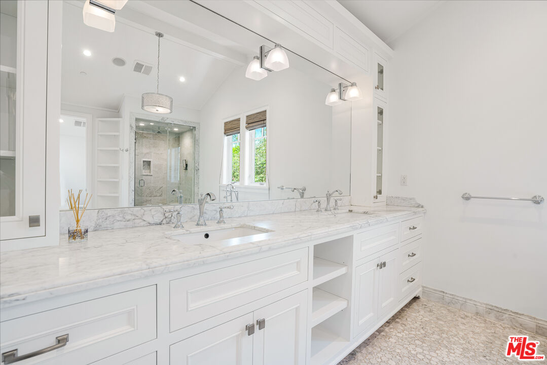 Bathroom with a long marble vanity, white cabinetry, and a glass-enclosed shower.