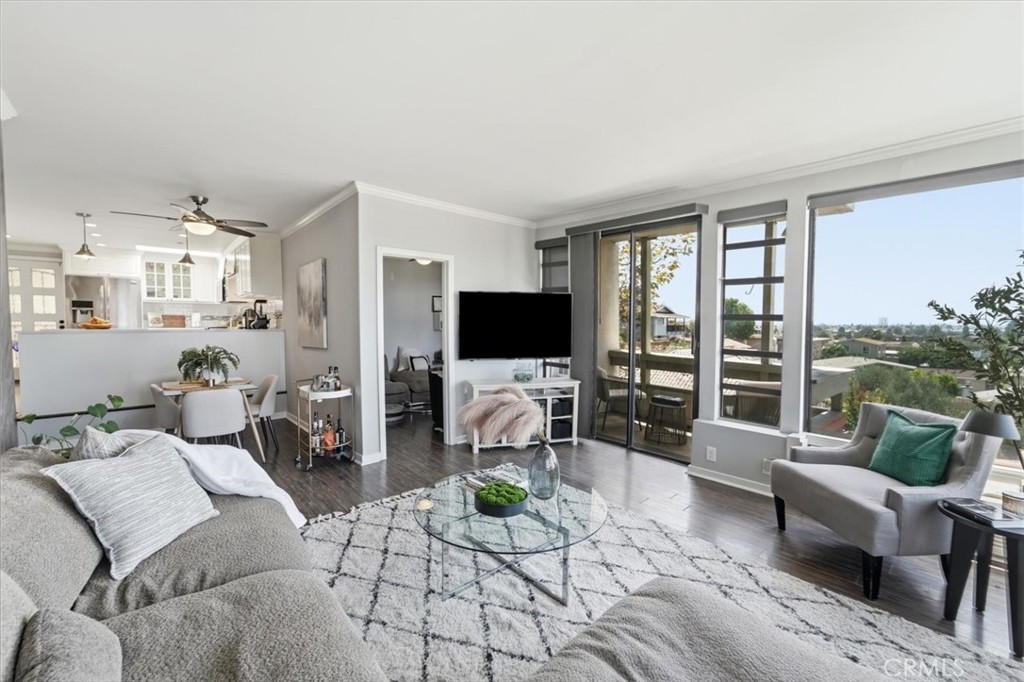 Open-plan living room with adjoining kitchen, balcony windows, and neighborhood views.