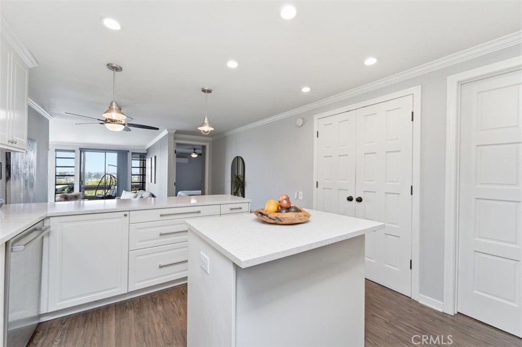 Bright kitchen with white cabinets and a large island opening to a living area.