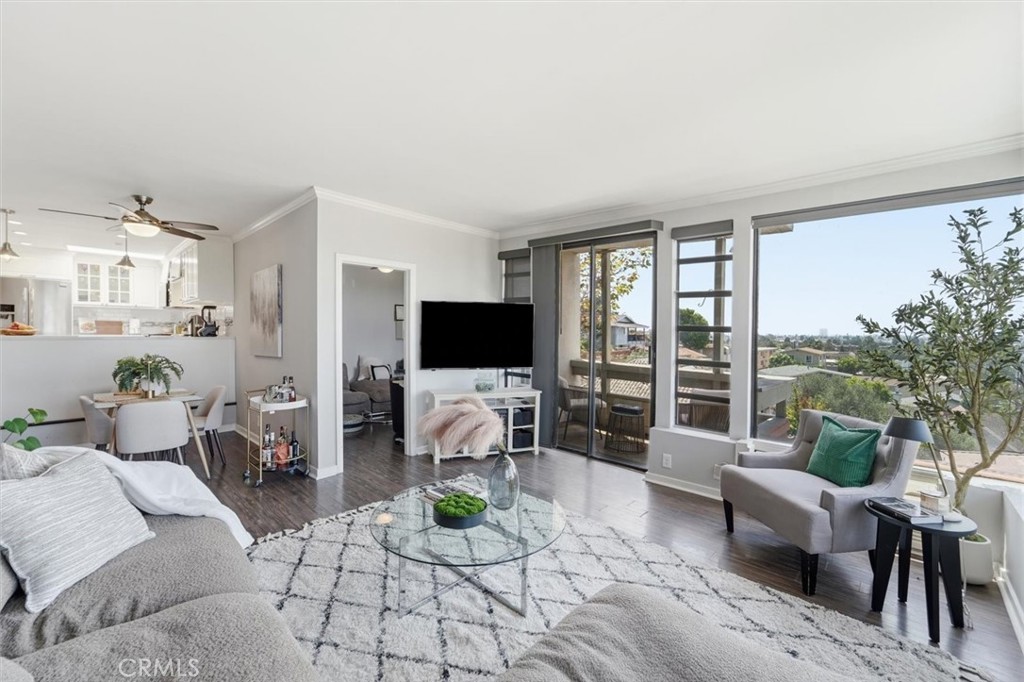 Open-plan living room with gray sofas, a glass coffee table, and large windows overlooking the neighborhood.